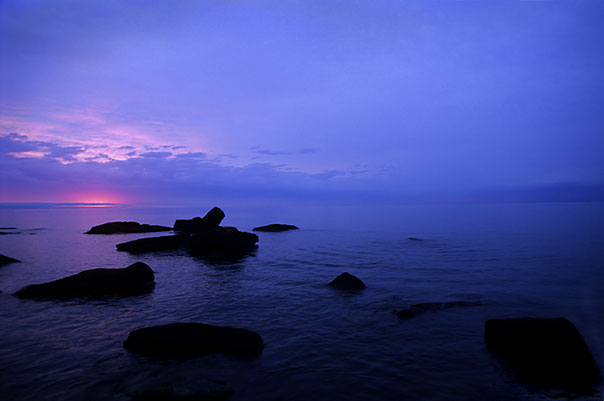 image of dark rocks near shore during sunset